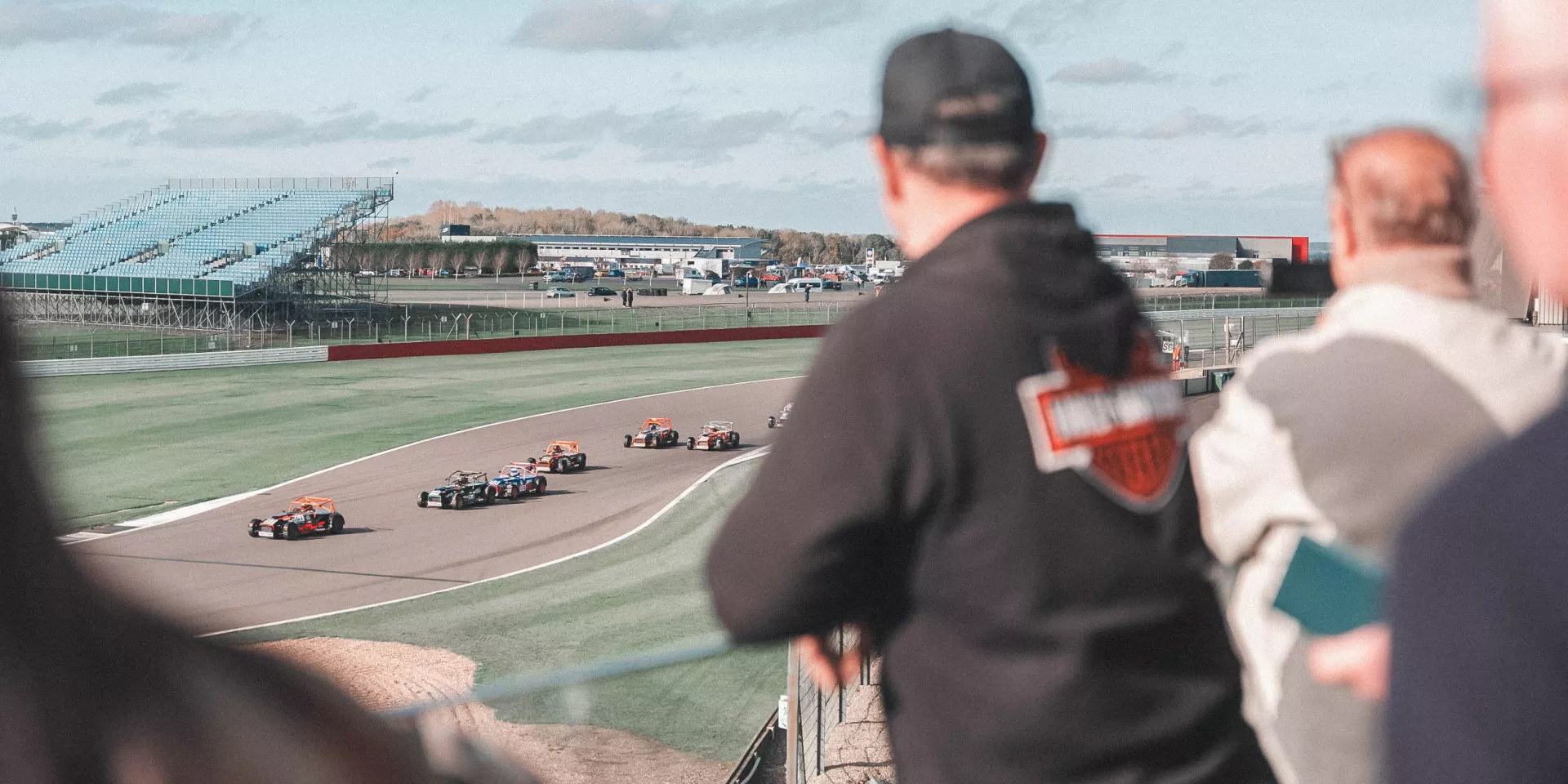 People looking at single seater race cars from the rooftop balcony at Escapade 